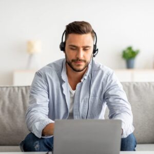Hotline support service. Millennial male call center operator in headset working with laptop at home